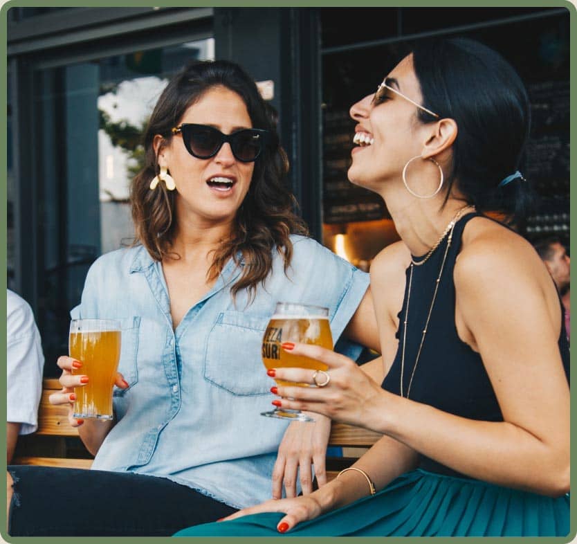 Two friends laughing over drinks